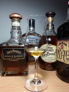 Assorted whiskey bottles with filled tasting glass
